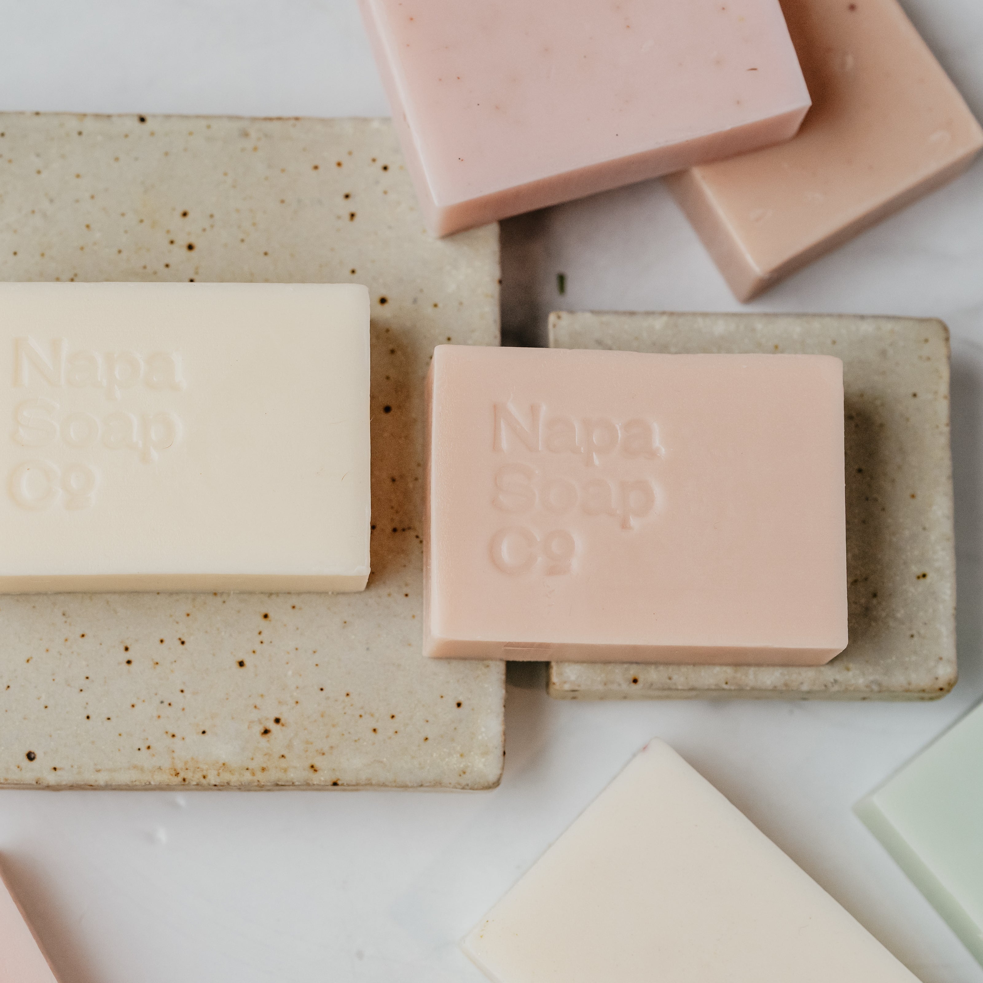 Various bars of soap on a textured surface with 'Napa Soap Co.' branding.