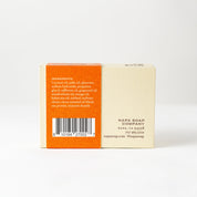 Back view of a soap bar with an orange label on a white background