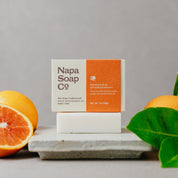 Napa Soap Co. soap bar with oranges and leaves on a gray background