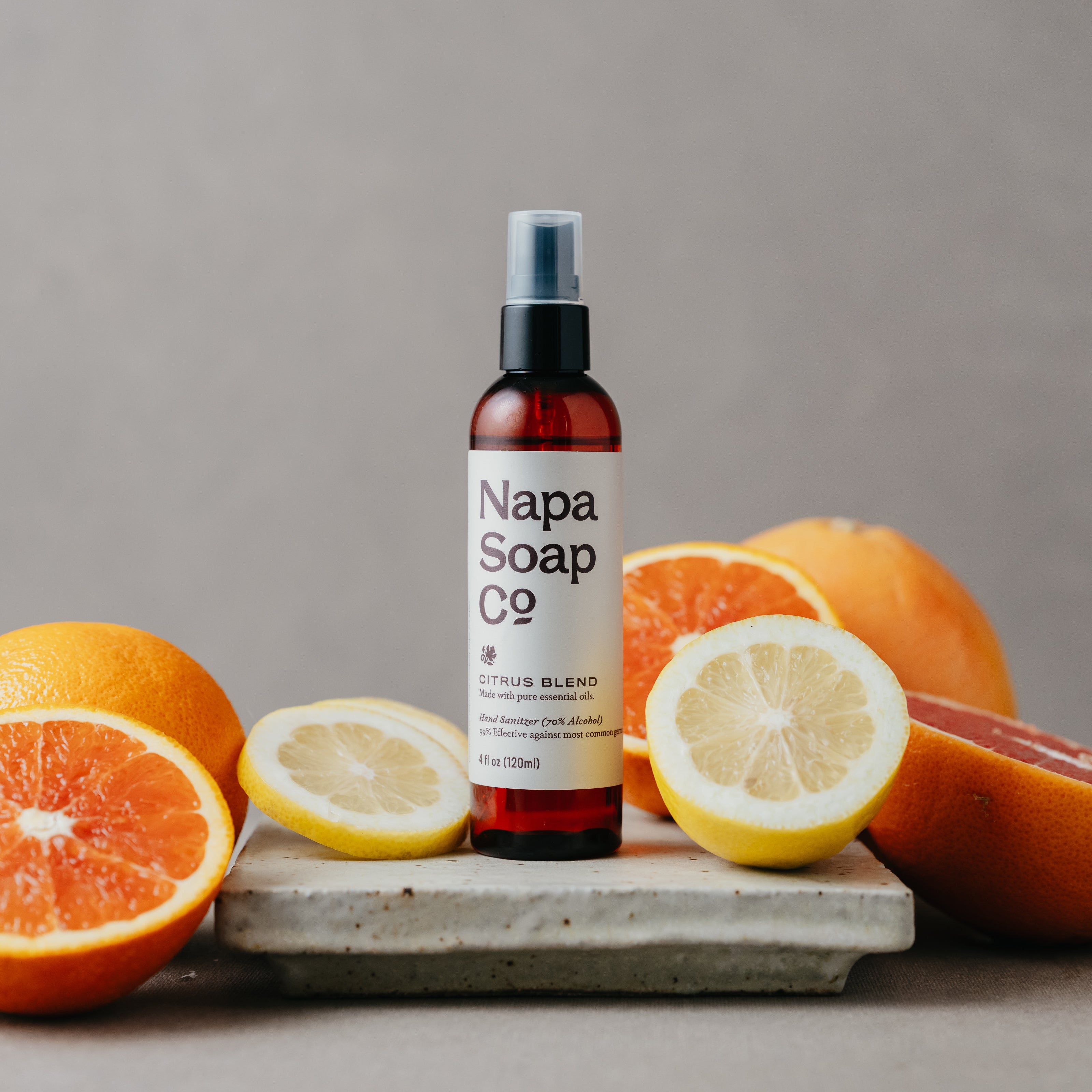 Napa Soap Co hand sanitizer bottle with citrus fruits on a gray background