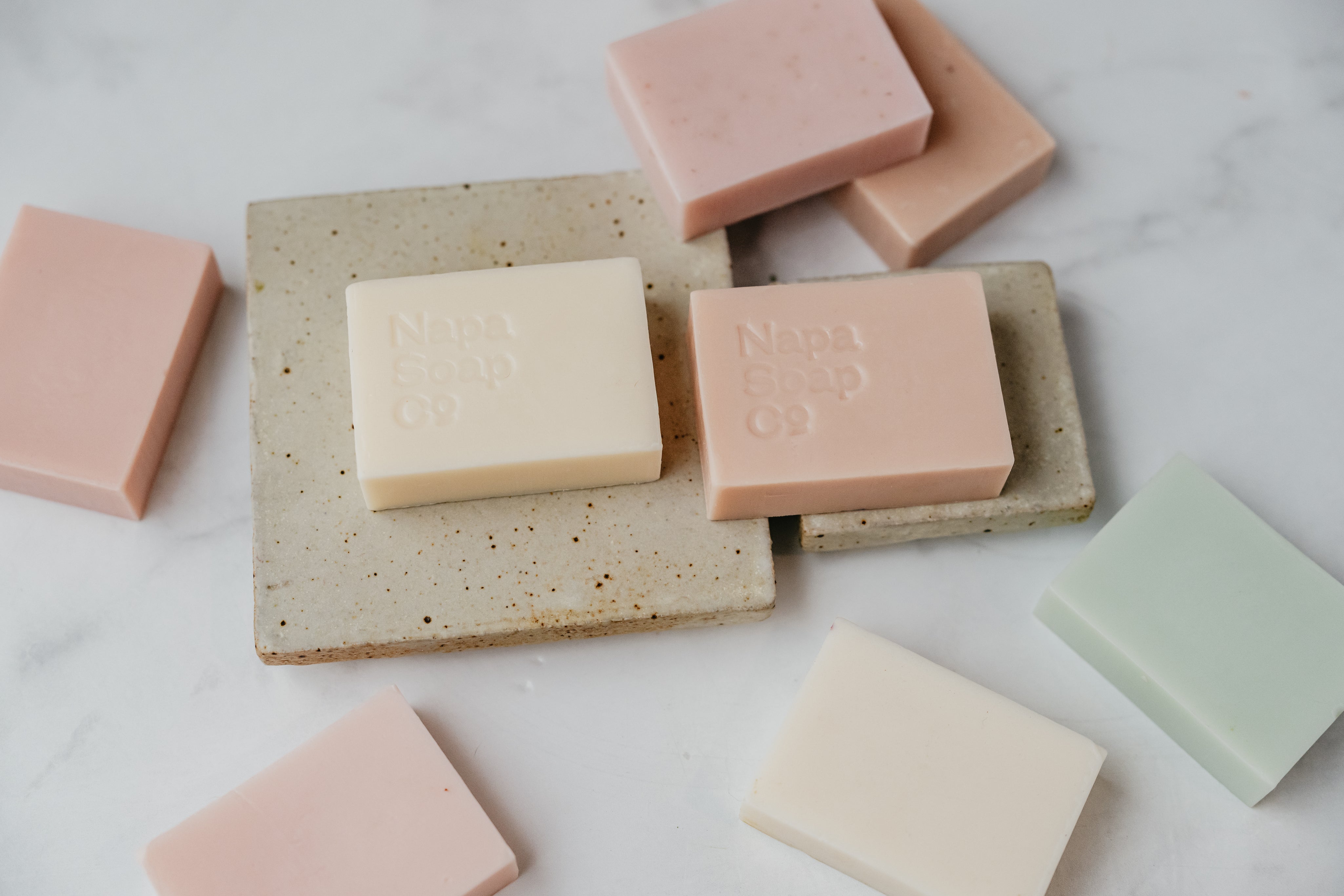 Various bars of soap on a stone soap dish with a marble background with Napa Soap Co branding