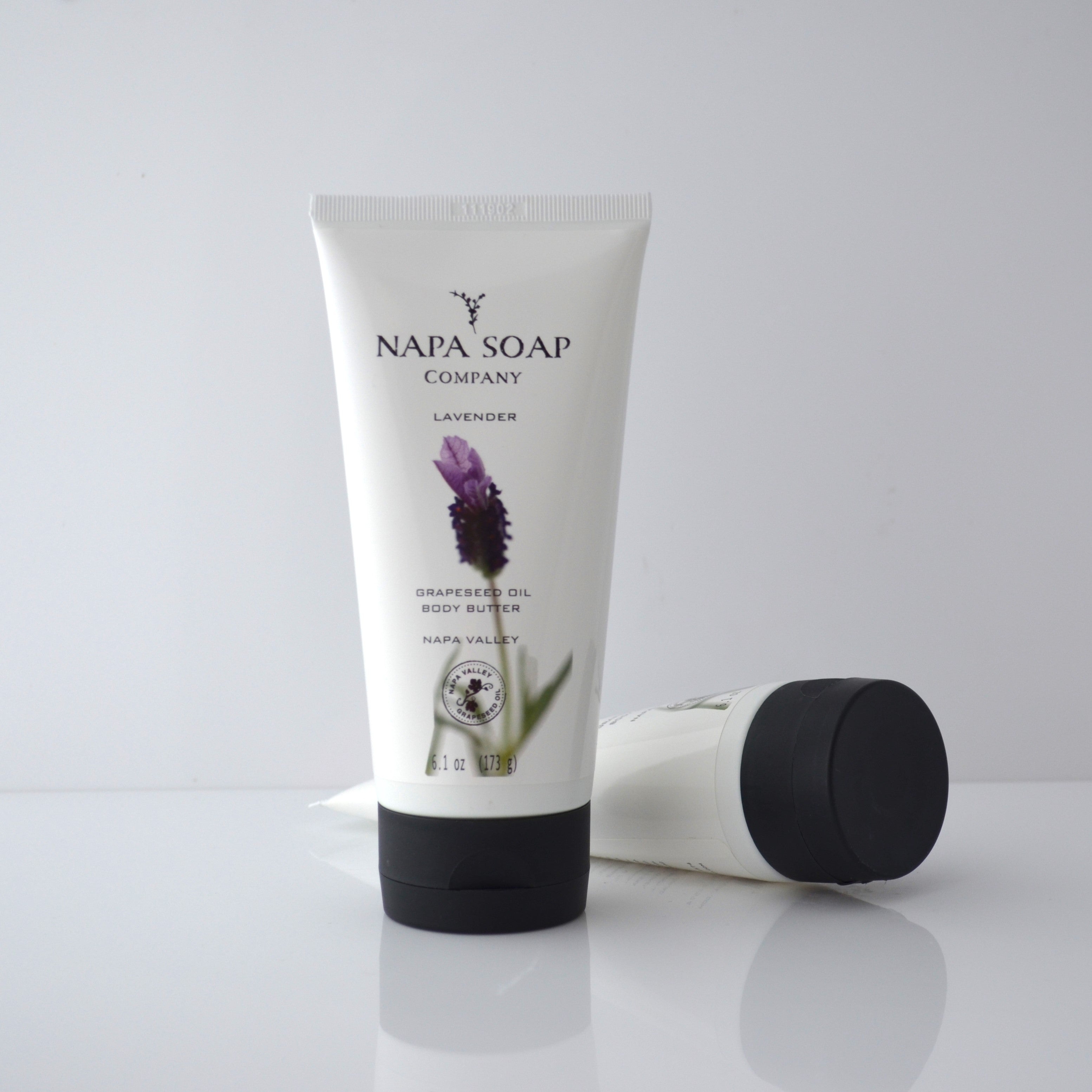 A tube of NAPA SOAP COMPANY body butter with a lavender flower illustration, next to its black cap, on a white background.